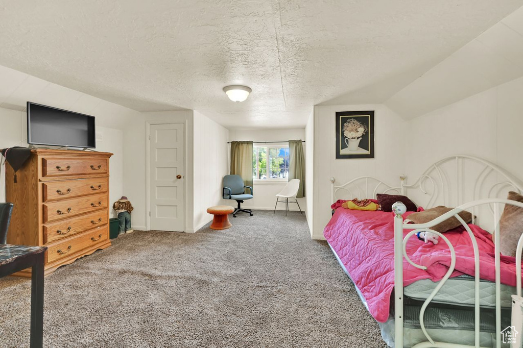 Carpeted bedroom with vaulted ceiling, a textured ceiling, and baseboards