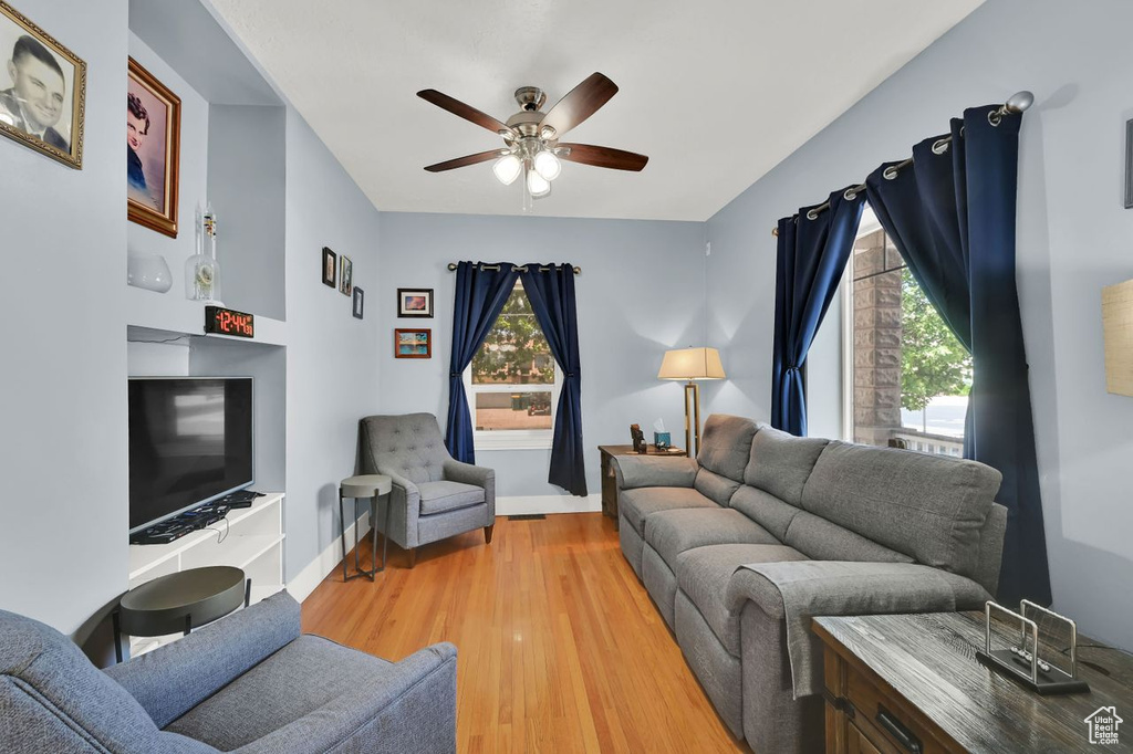 Living area with a ceiling fan, light wood-style flooring, and baseboards