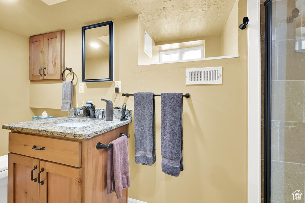 Bathroom with vanity, a shower with door, and toilet
