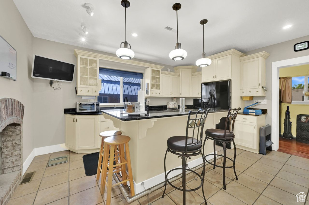 Kitchen with fridge with ice dispenser, light tile patterned floors, dark countertops, cream cabinetry, and recessed lighting