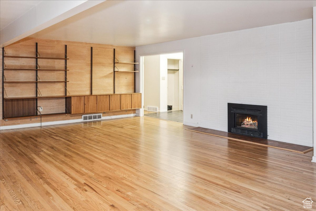 Unfurnished living room with wood finished floors and a tiled fireplace