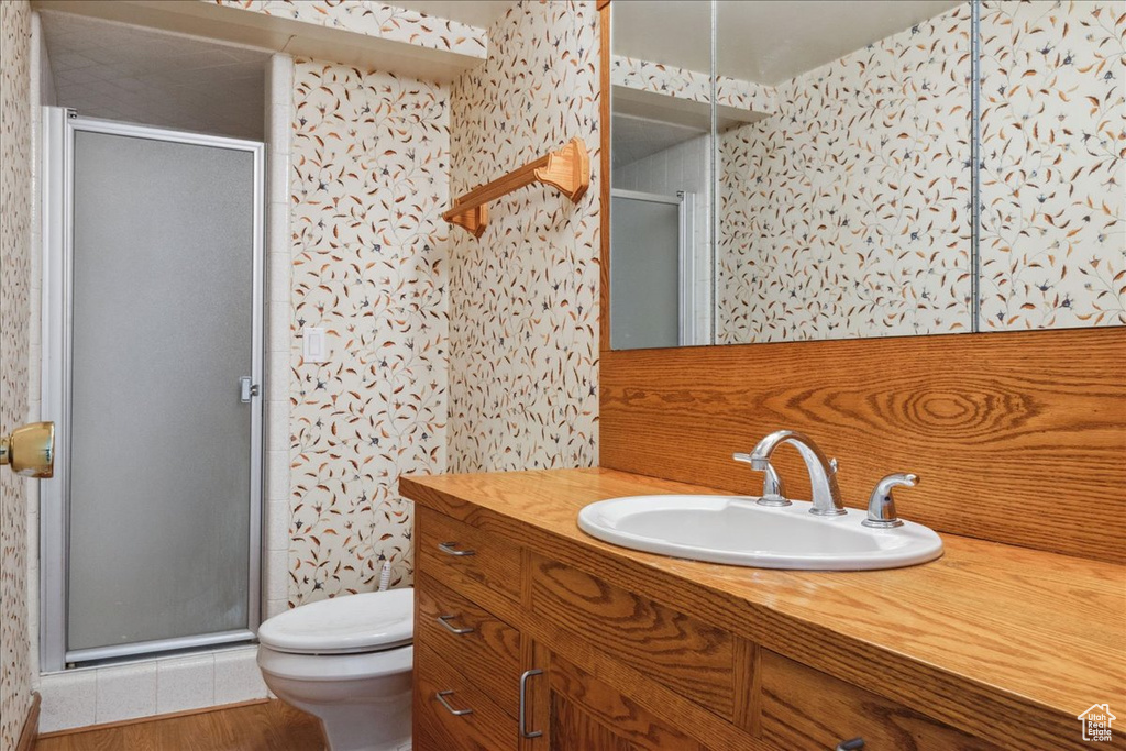 Full bath with vanity, a shower stall, toilet, and wallpapered walls