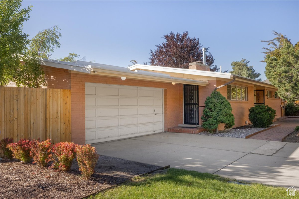 View of front facade with an attached garage, brick siding, a chimney, and driveway