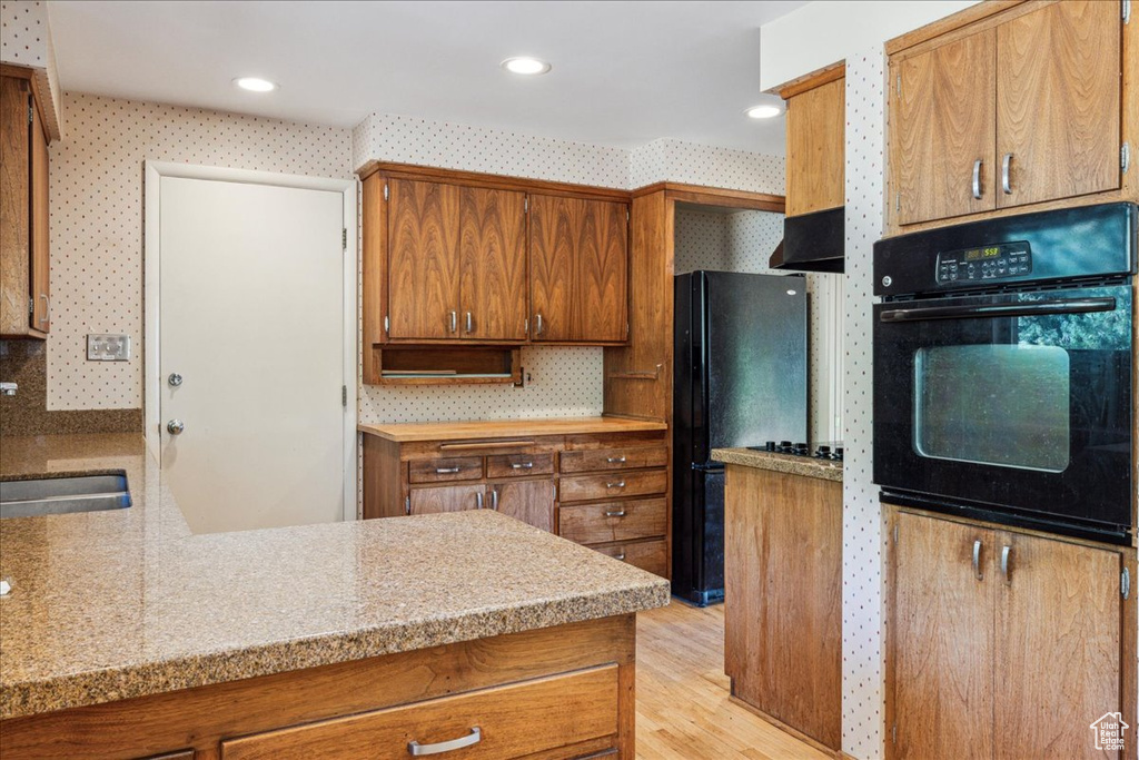 Kitchen with black appliances, a sink, brown cabinetry, light countertops, and recessed lighting