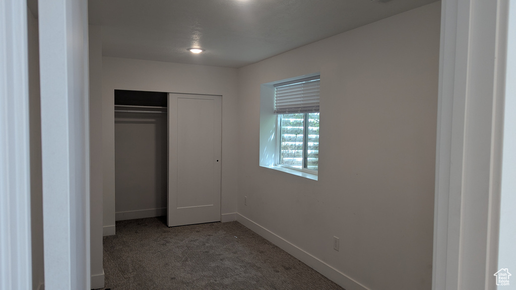Unfurnished bedroom featuring carpet, baseboards, and a closet