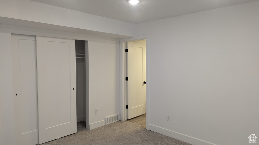 Unfurnished bedroom with light colored carpet, baseboards, and a closet