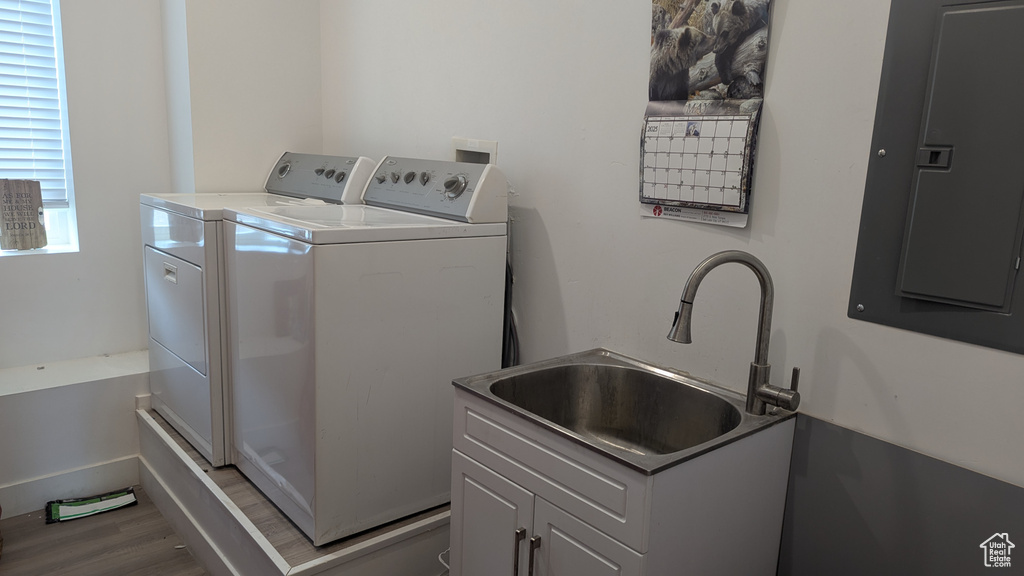 Laundry area with washer and dryer, wood finished floors, electric panel, and cabinet space