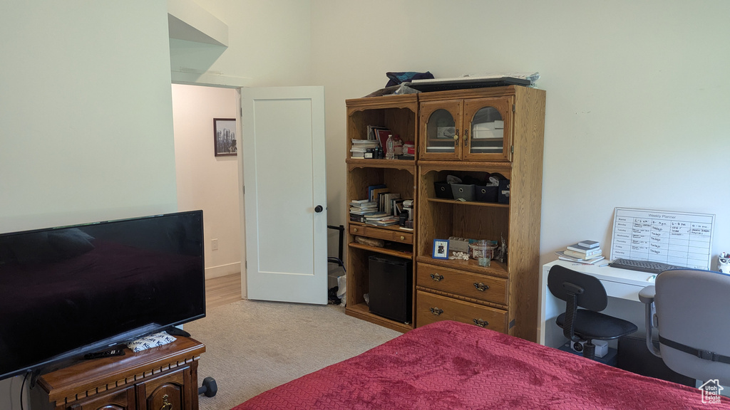 Bedroom featuring light colored carpet and a desk