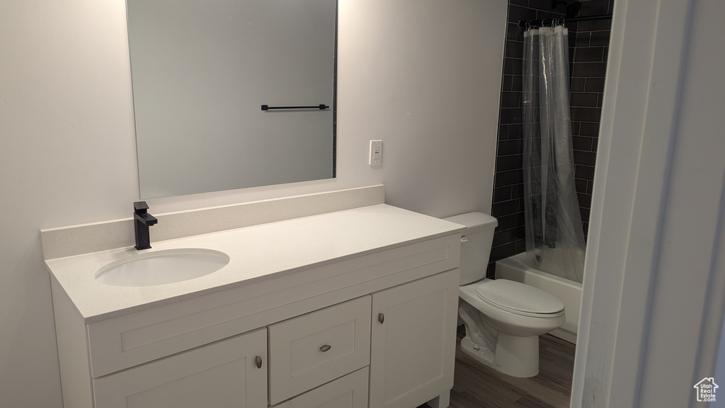 Full bath featuring toilet, vanity, shower / bath combo with shower curtain, and wood finished floors