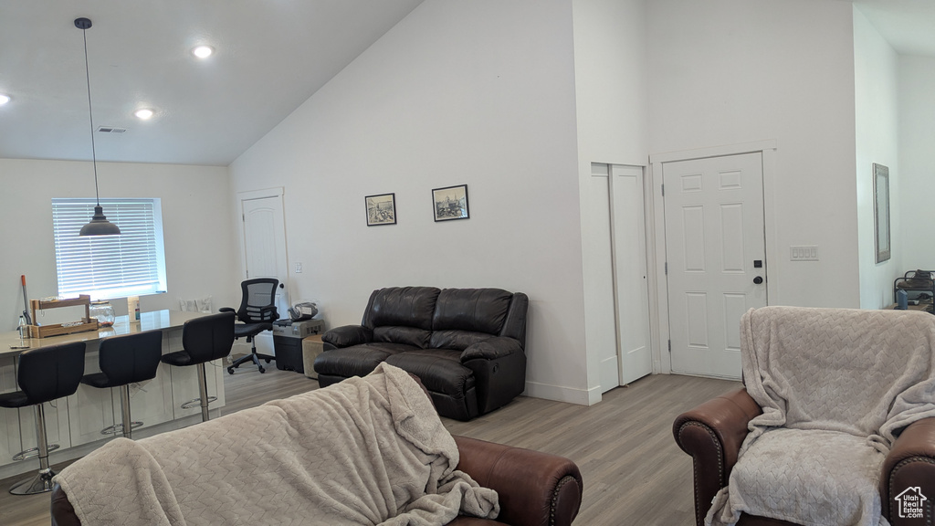 Living room featuring high vaulted ceiling, light wood finished floors, baseboards, and recessed lighting