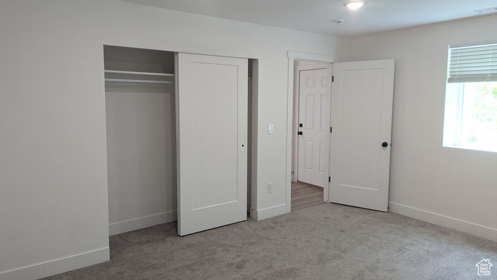 Unfurnished bedroom featuring carpet flooring, baseboards, and a closet