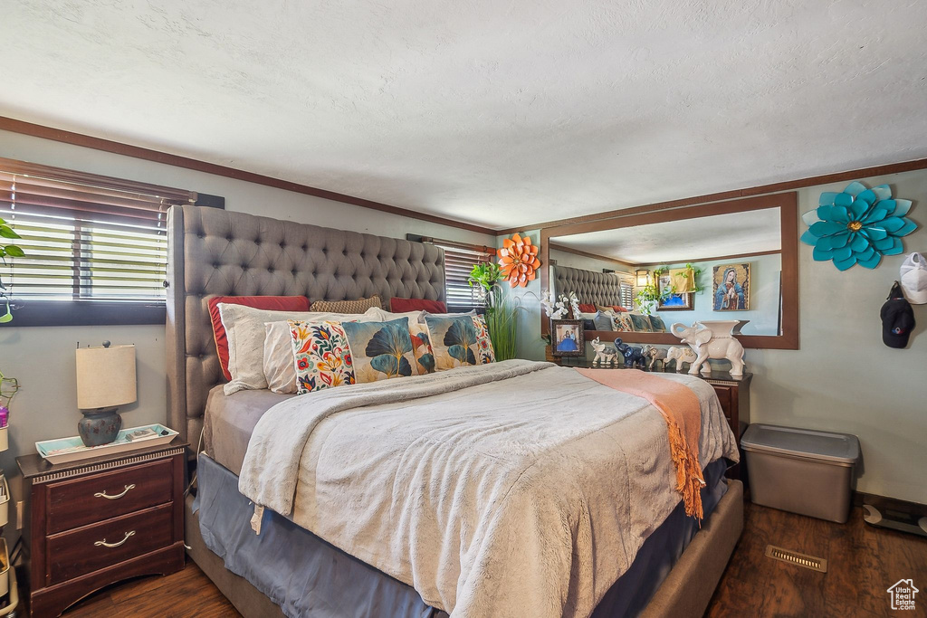Bedroom with wood finished floors, multiple windows, and ornamental molding