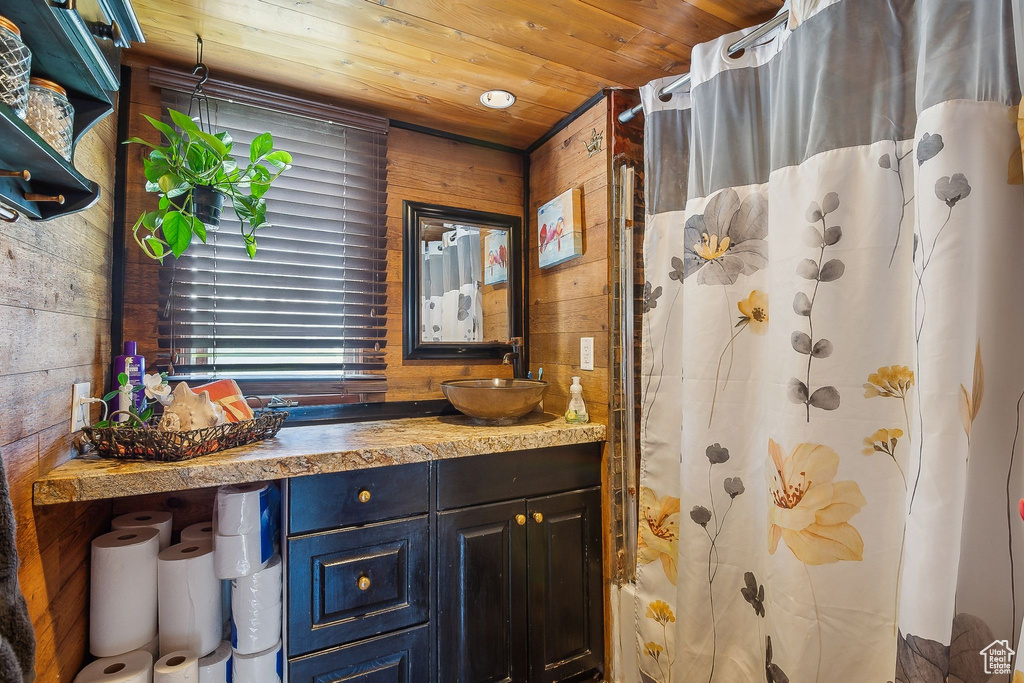 Bathroom featuring wooden walls, vanity, curtained shower, and wood ceiling