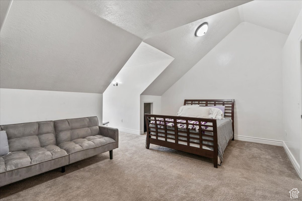 Bedroom featuring carpet flooring, vaulted ceiling, a textured ceiling, and baseboards