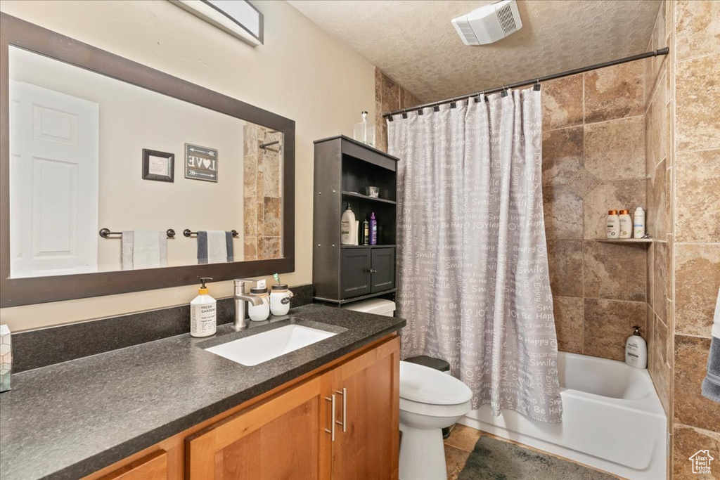 Full bath with vanity, toilet, shower / bathtub combination with curtain, tile patterned floors, and a textured ceiling