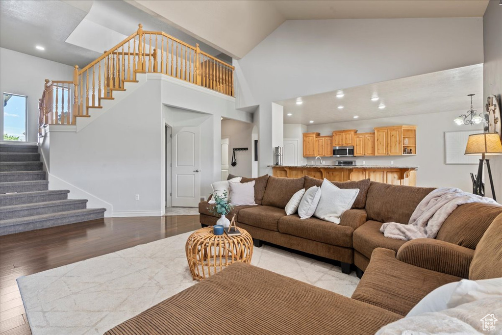 Living area with stairs, light wood finished floors, high vaulted ceiling, baseboards, and recessed lighting