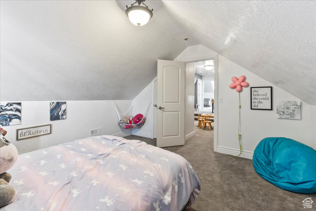 Carpeted bedroom with a textured ceiling, lofted ceiling, and baseboards