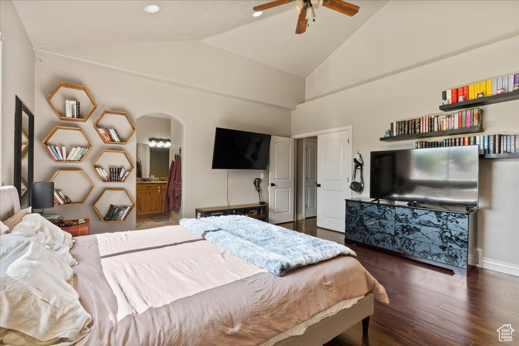 Bedroom featuring vaulted ceiling, wood finished floors, arched walkways, connected bathroom, and a ceiling fan