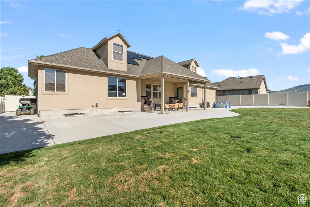 Back of house featuring roof mounted solar panels, a patio area, roof with shingles, and stucco siding