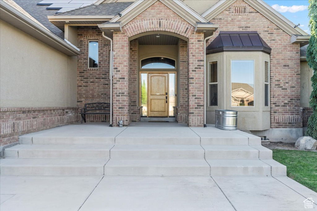 View of exterior entry featuring brick siding and roof with shingles