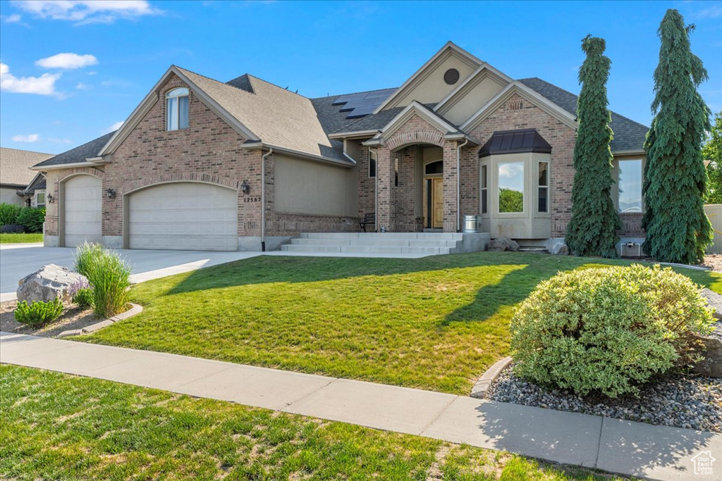 View of front facade featuring a front lawn, concrete driveway, brick siding, and a garage