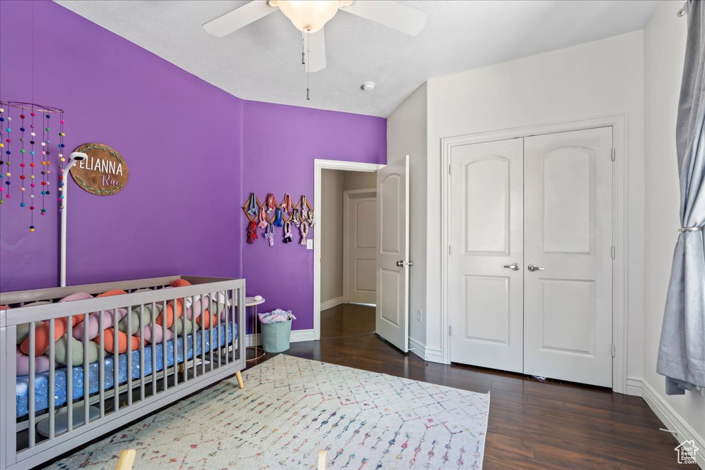 Bedroom with wood finished floors, baseboards, a closet, and a crib