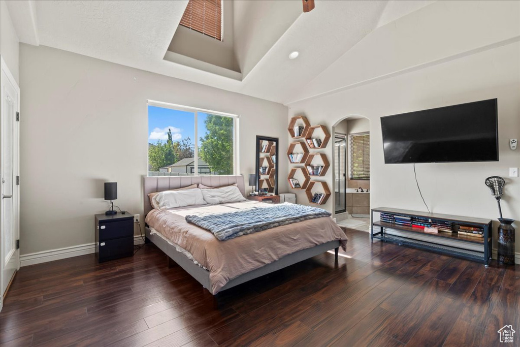 Bedroom featuring hardwood / wood-style floors, arched walkways, vaulted ceiling, baseboards, and ensuite bathroom