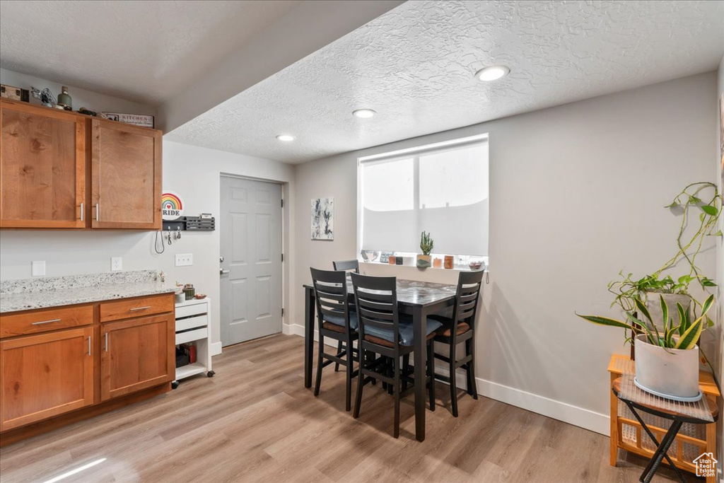 Dining space featuring light wood-style floors, baseboards, a textured ceiling, and recessed lighting