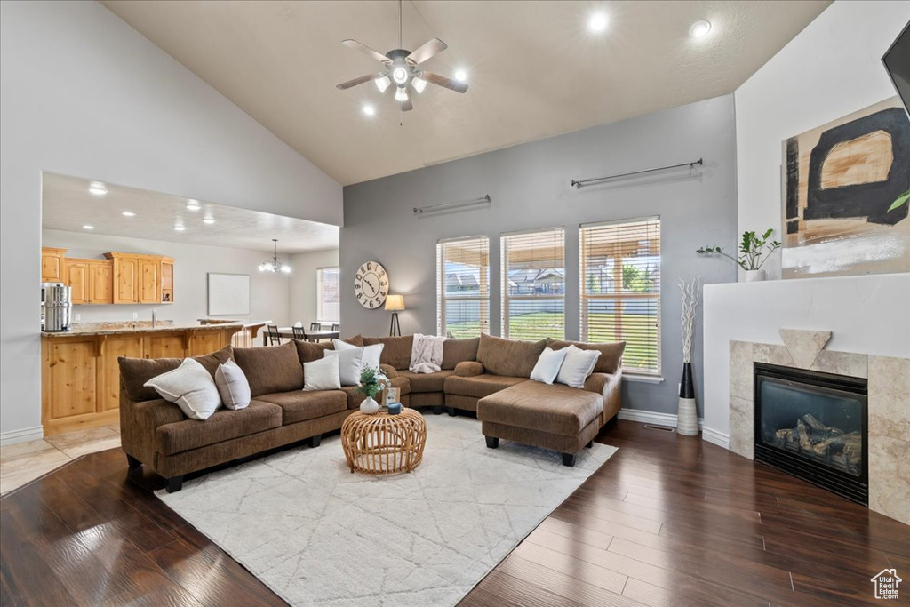 Living area with high vaulted ceiling, a ceiling fan, wood finished floors, baseboards, and recessed lighting