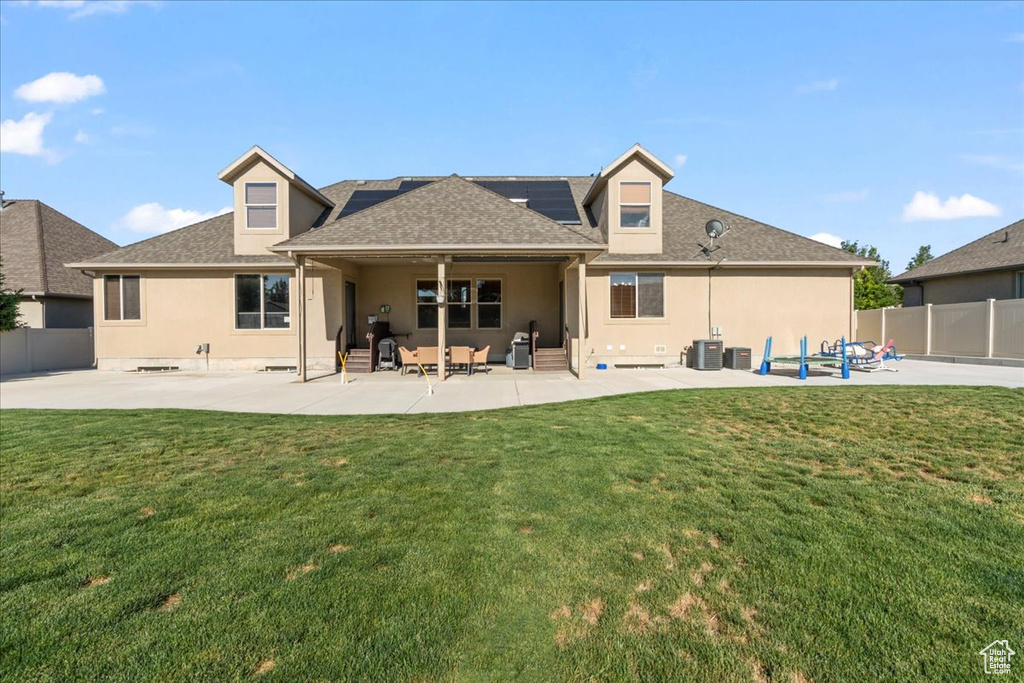 Back of property featuring roof mounted solar panels, a patio, stucco siding, central air condition unit, and a shingled roof