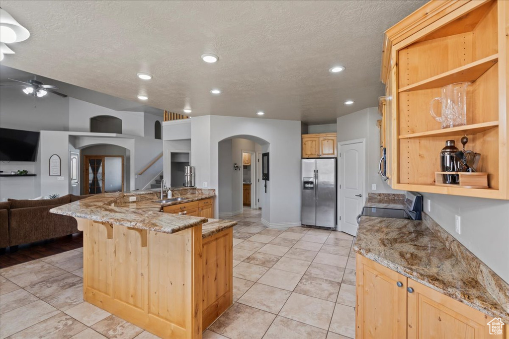 Kitchen with appliances with stainless steel finishes, arched walkways, open floor plan, a sink, and ceiling fan