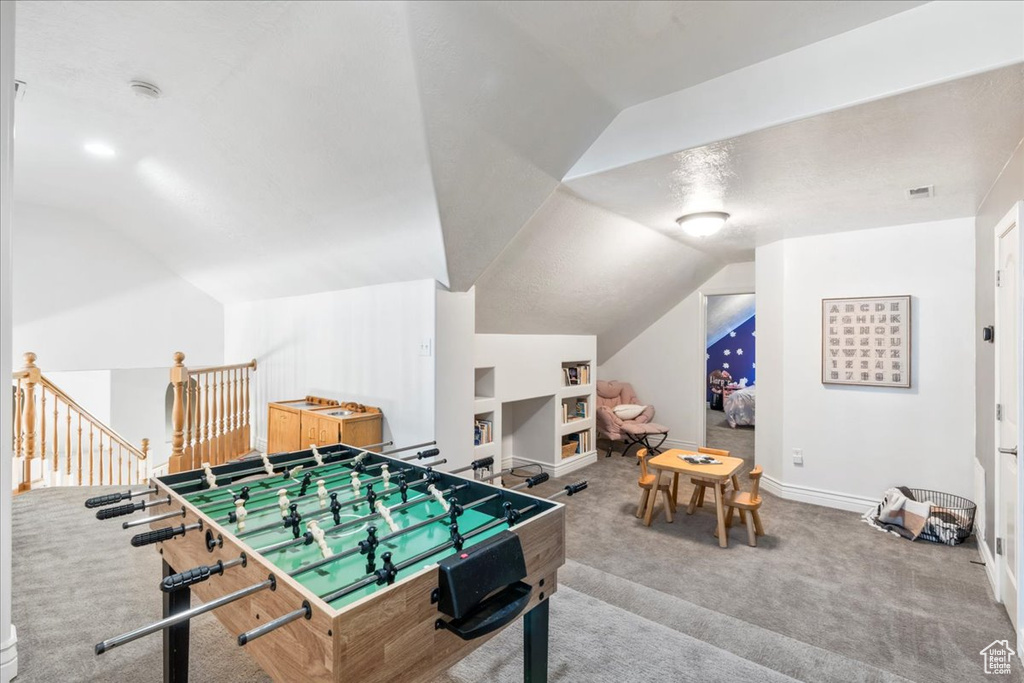 Recreation room featuring lofted ceiling, carpet flooring, baseboards, and built in features