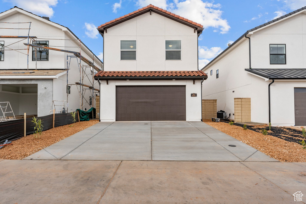 Mediterranean / spanish home featuring a tiled roof, an attached garage, stucco siding, and concrete driveway