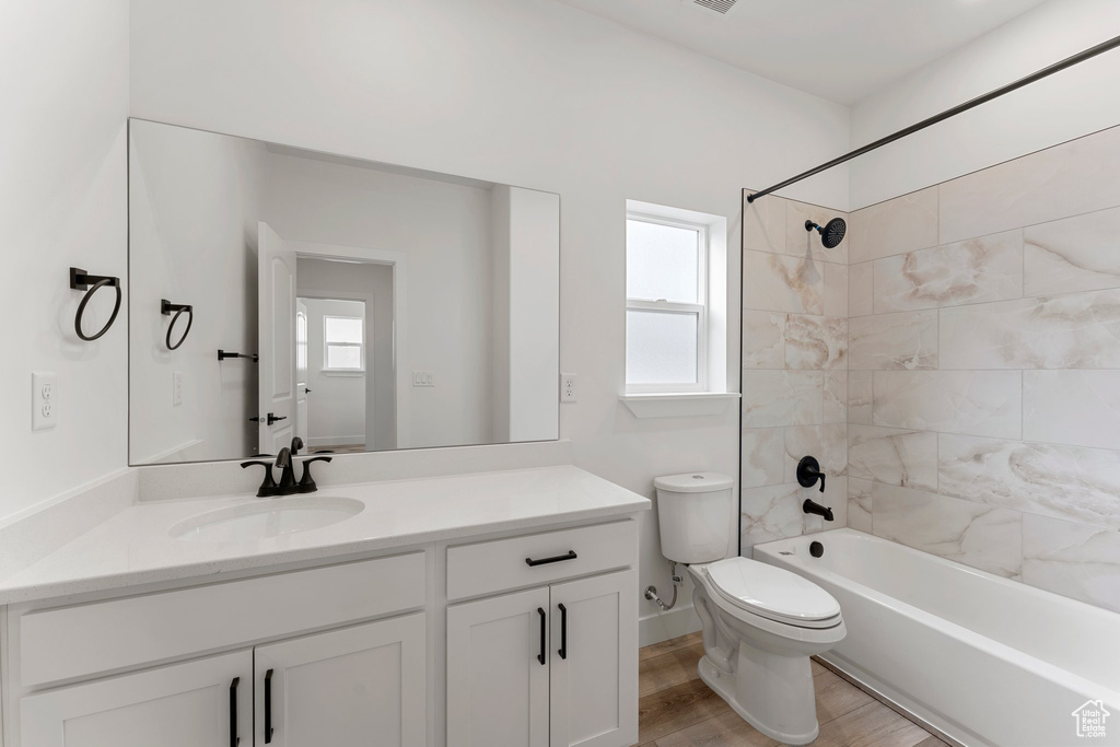 Bathroom featuring toilet, vanity, tub / shower combination, and wood finished floors