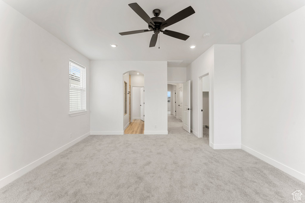 Unfurnished bedroom with arched walkways, baseboards, light colored carpet, recessed lighting, and a ceiling fan