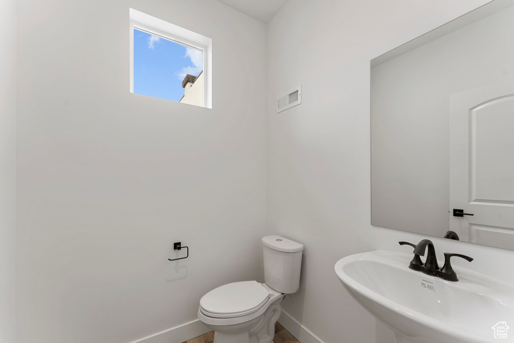 Bathroom featuring a sink, toilet, and baseboards