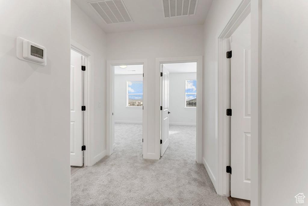 Hallway with light carpet and baseboards