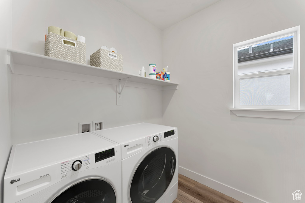 Laundry room featuring washer and clothes dryer, light wood-style flooring, and baseboards