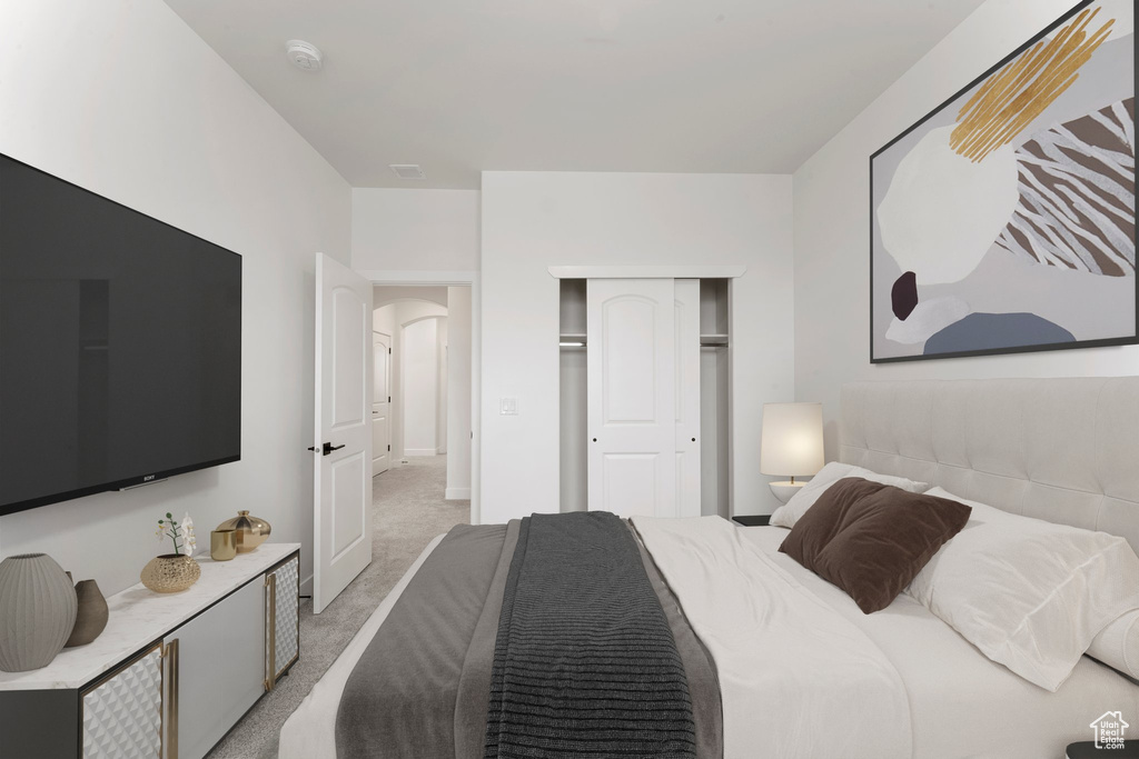 Bedroom with light colored carpet, a closet, and arched walkways
