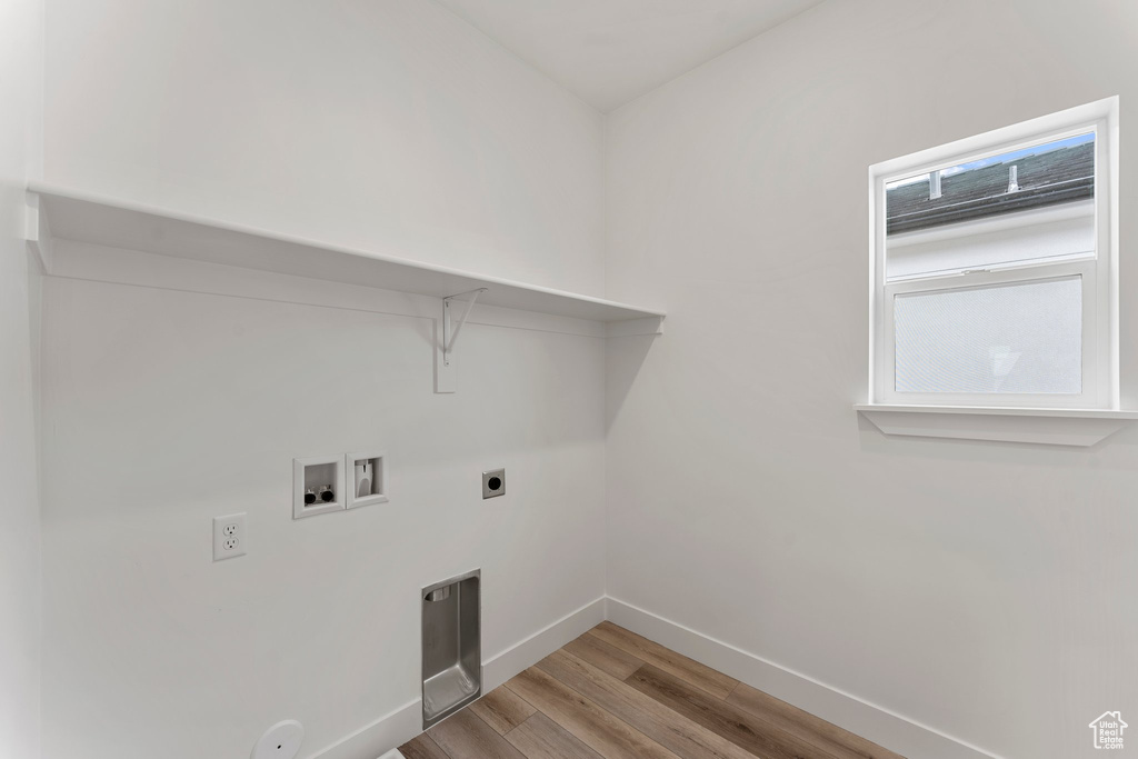 Laundry room featuring light wood-type flooring, hookup for a washing machine, baseboards, and hookup for an electric dryer