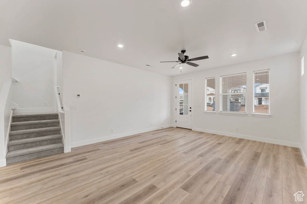 Unfurnished living room featuring stairway, ceiling fan, recessed lighting, light wood-style flooring, and baseboards