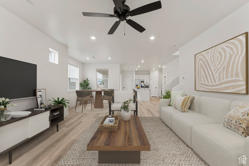 Living area with light wood-type flooring, a ceiling fan, and recessed lighting
