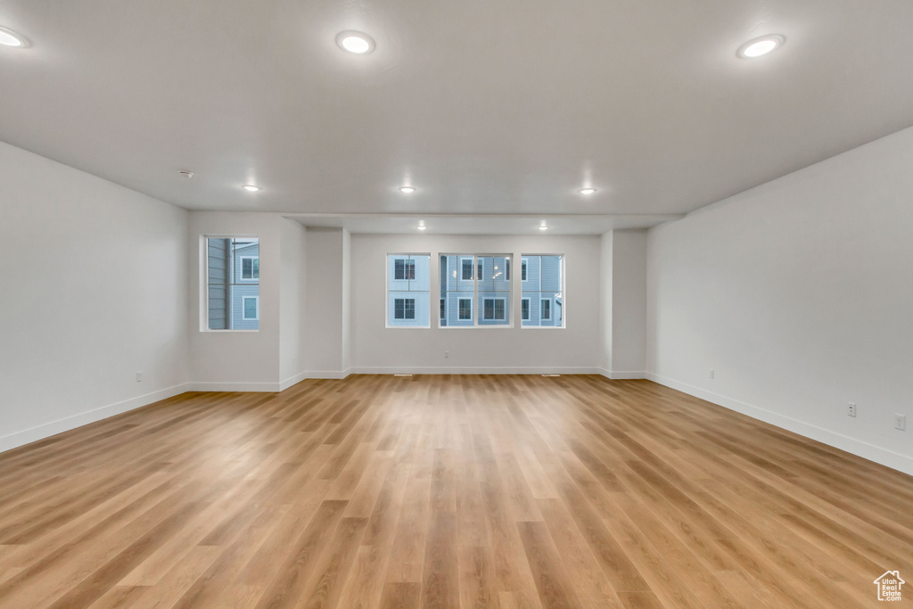 Unfurnished living room with baseboards, light wood-style floors, healthy amount of natural light, and recessed lighting