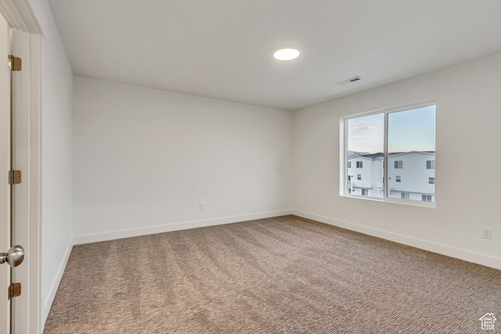 Carpeted spare room featuring baseboards