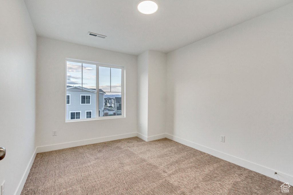 Carpeted spare room featuring baseboards