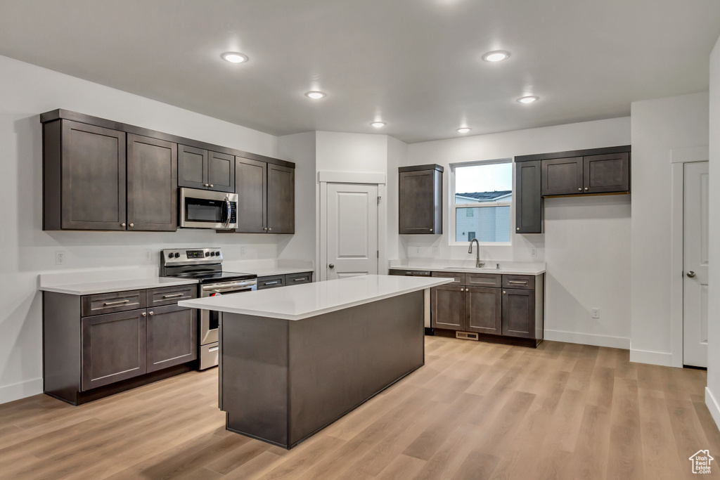 Kitchen with stainless steel appliances, light wood-style floors, light countertops, baseboards, and recessed lighting