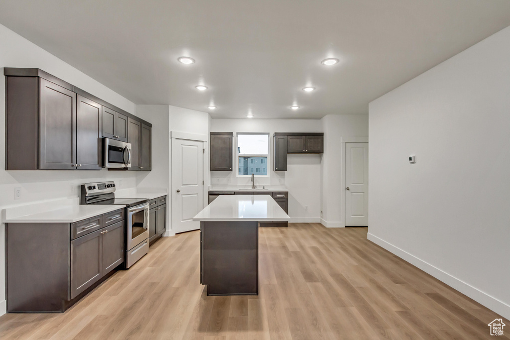 Kitchen with stainless steel appliances, a sink, light wood-style flooring, light countertops, and recessed lighting