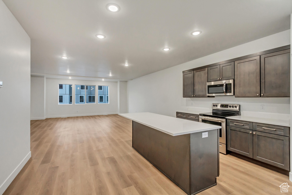 Kitchen with stainless steel appliances, a kitchen island, light wood finished floors, light countertops, and recessed lighting