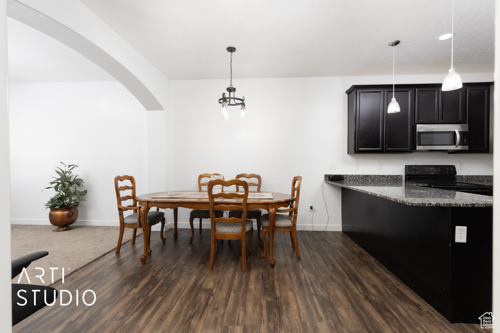 Dining area featuring arched walkways, baseboards, and dark wood-style floors