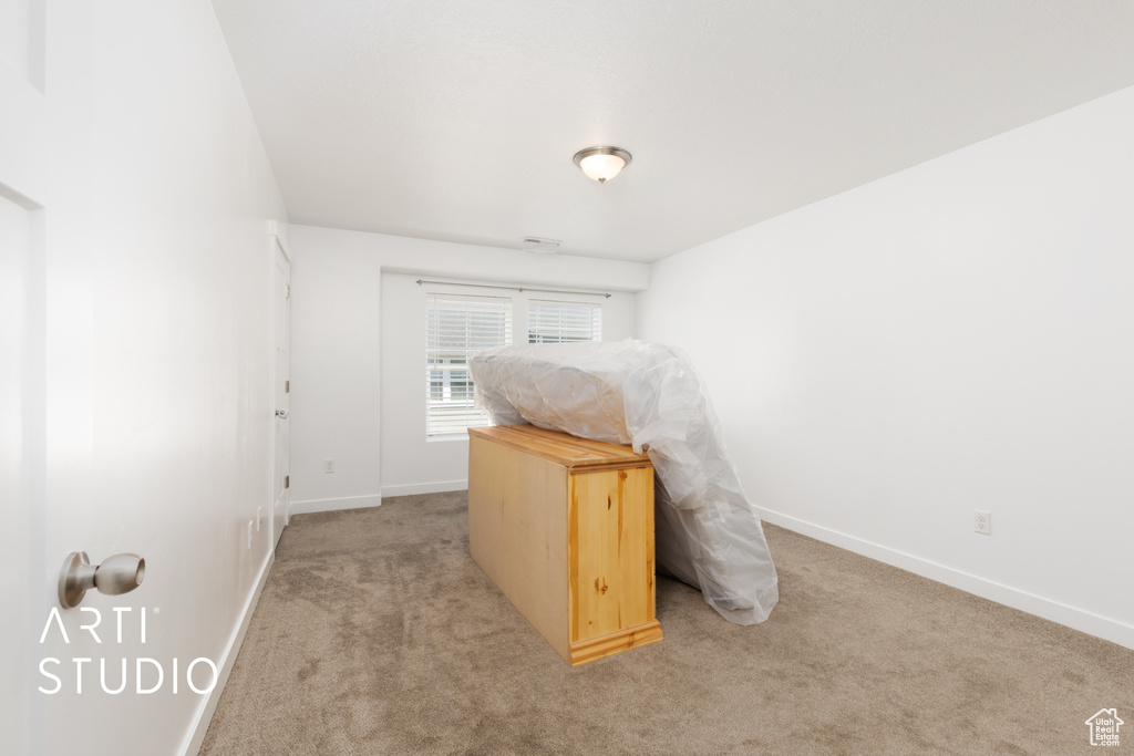 Unfurnished bedroom featuring baseboards and light carpet